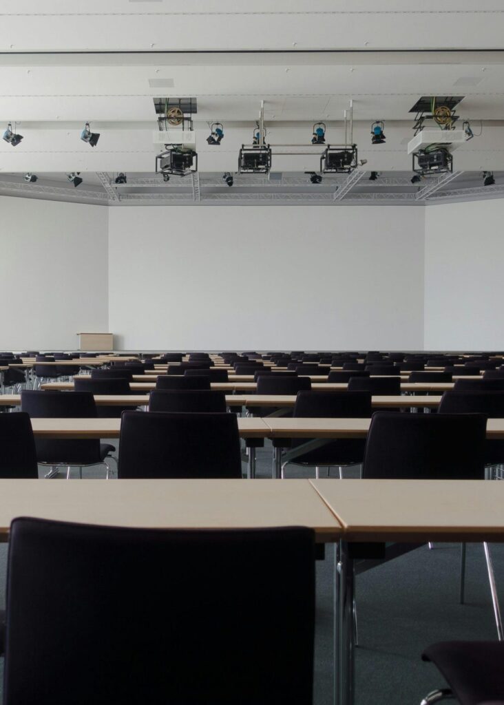 Spacious contemporary conference room with rows of tables and chairs, ready for meetings.